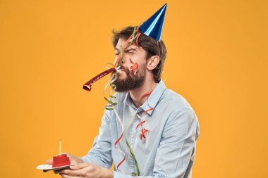 Kafasında sarı arka planda doğum günü şapkası olan neşeli bir adam.