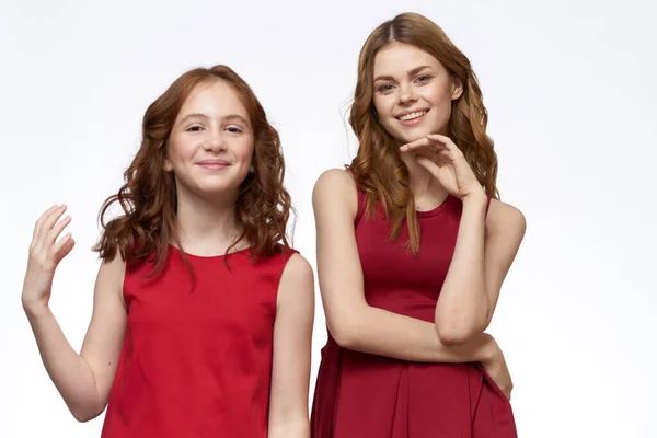 Fröhlich Mutter und Tochter neben roten Kleidern Umarmungen Lifestyle Licht Hintergrund Lächeln — Stockfoto