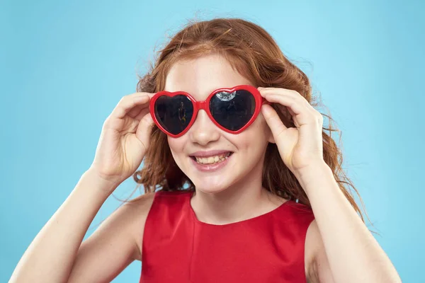 女の子でサングラスで心の形で赤いドレス巻き毛青の背景 — ストック写真