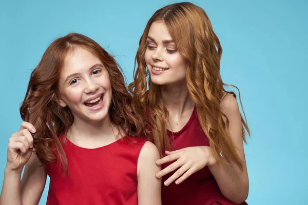 Familie Mutter und Tochter umarmen rote Kleider Kommunikation Emotionen blauer Hintergrund — Stockfoto