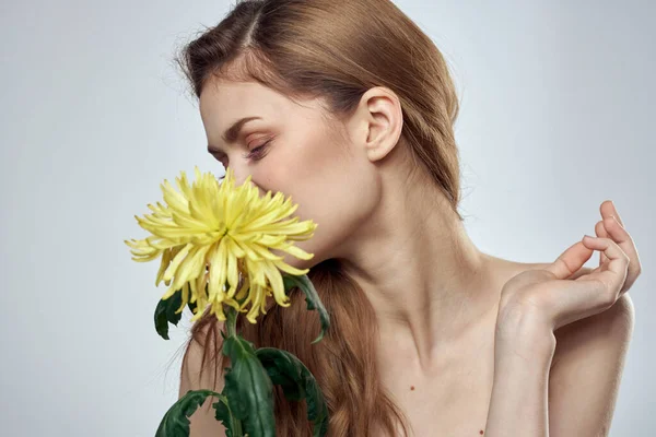 Retrato de uma mulher bonita com uma flor amarela em um fundo claro cortado com Copiar modelo de espaço — Fotografia de Stock