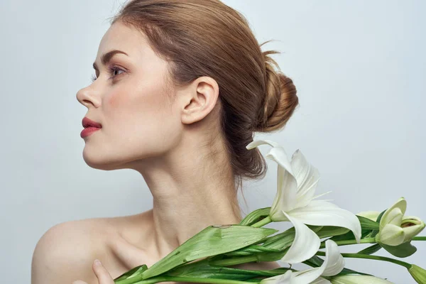 Hermosa chica con un ramo de flores blancas sobre un fondo claro hombros desnudos piel limpia primavera — Foto de Stock