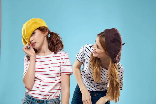 모자를 쓰고 즐거운 생활을 하는 파란색 배경 스튜디오의 패션 자매들 — 스톡 사진
