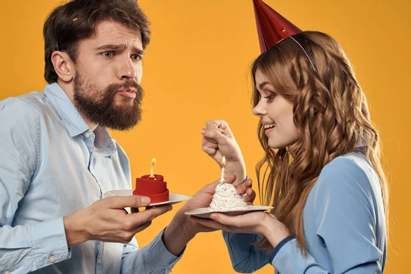 Narozeninová party muž a žena v čepici s dort na žlutém pozadí oříznutý pohled — Stock fotografie