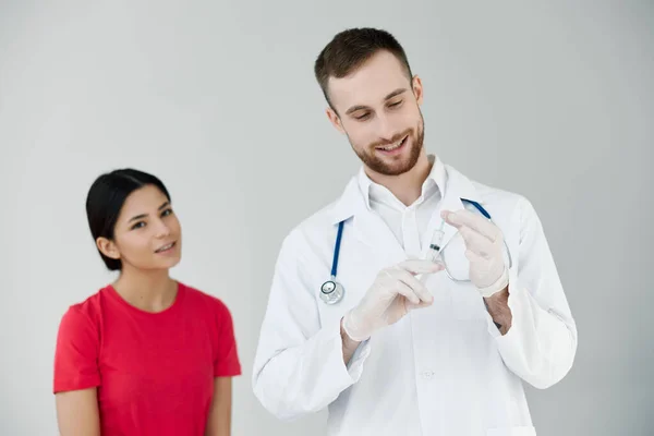 Medico di sesso maschile con un cappotto bianco accanto al paziente tiene un'iniezione nelle mani vaccinazione covid — Foto Stock