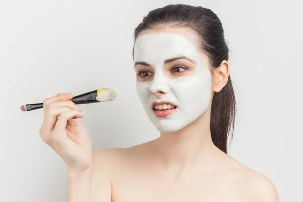 Mujer con hombros desnudos con un cepillo en las manos aplicando maquillaje —  Fotos de Stock
