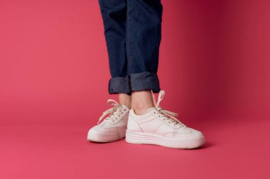 Kadın bacakları kot beyaz spor ayakkabılar sokak moda stüdyosu pembe arka plan