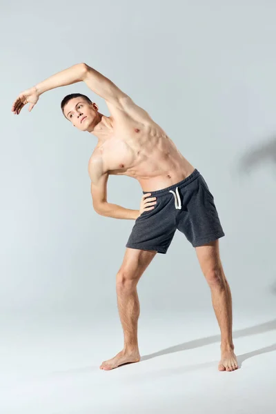 Atleta con los músculos inflados del brazo doblados hacia un lado sobre un fondo gris — Foto de Stock