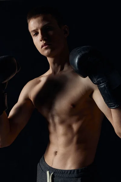 Boxer in black gloves on a dark background inflated torso bodybuilder — Stock Photo, Image