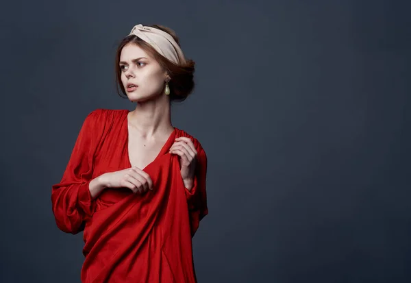 Mulher atraente em vestido vermelho decorando turbante em sua cabeça estúdio corte vista — Fotografia de Stock
