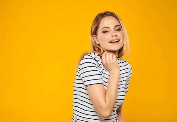 Happy blonde on a yellow background in a striped T-shirt emotions cropped view