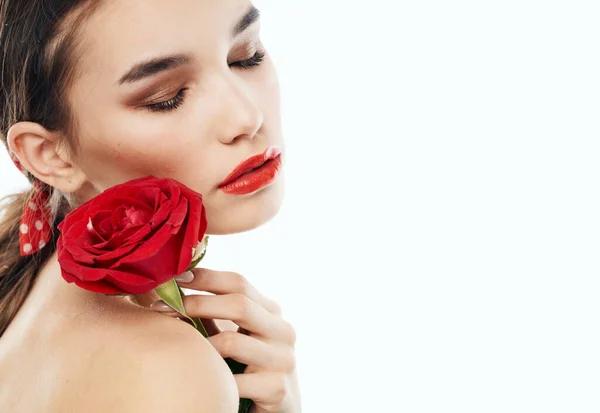 Jovencita con hombros desnudos y una flor roja cerca de su cara — Foto de Stock