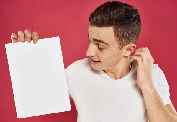 Een man gebaart met zijn handen en een wit vel papier reclame flyer — Stockfoto