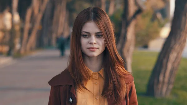 Jolie femme en manteau avec un téléphone en main marchant dans le parc reste — Photo