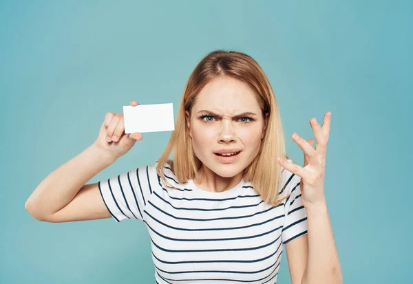 Женщина в полосатой футболке держит визитку в руке на синем фоне — стоковое фото