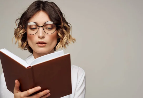 Femme avec un bloc-notes dans les mains et portant des lunettes sur un fond gris vue recadrée d'une chemise Light — Photo