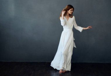 Beyaz elbiseli çekici kadın göz kamaştırıcı gri arka plan