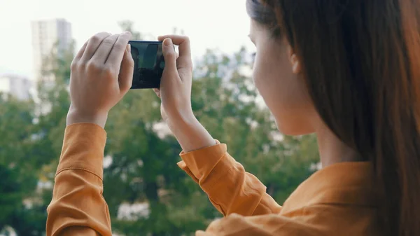 Woman with phone in hand in nature taking pictures of nature outdoors — Stock Photo, Image