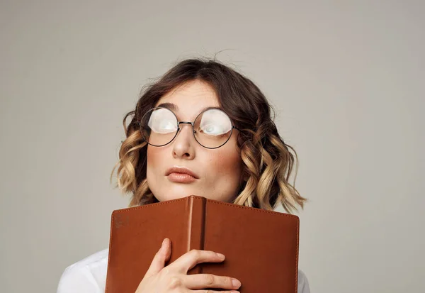 Femme avec des lunettes tient un livre dans sa main sur un fond gris modèle de coiffure courte — Photo