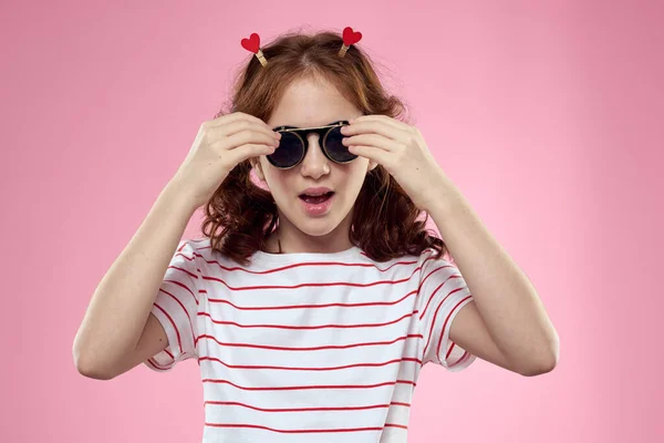 Cheerful little girl with sunglasses fashionable clothes studio pink background — 스톡 사진