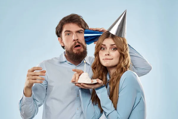 Joyeux homme et femme soufflant bougies gâteau décoration de vacances fond bleu — Photo