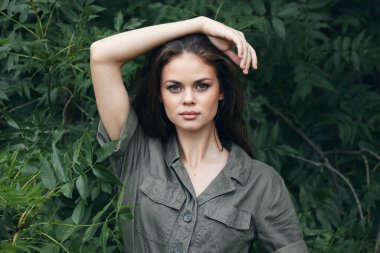 Ormandaki kadın elini başının üstünde tutar ve yeşil tulum bırakır. 