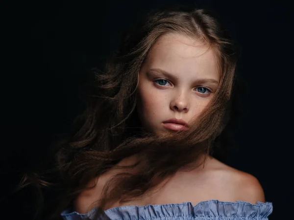 Modisches Mädchen in einem Kleid auf dunklem Hintergrund lockige Haare blaue Augen — Stockfoto