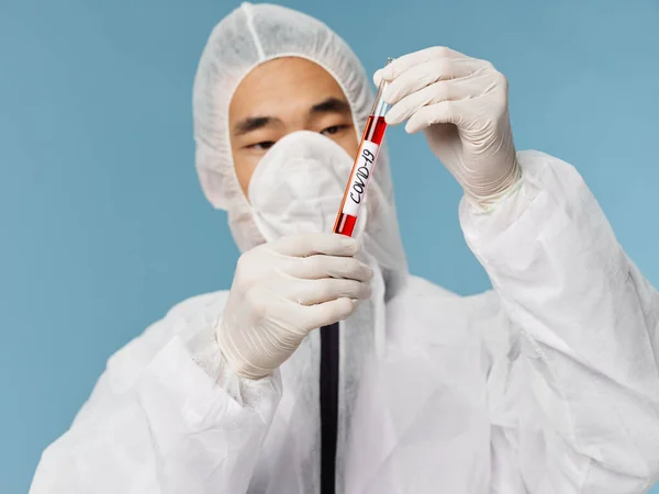 Asistente de laboratorio masculino sostiene sangre en sus manos para las pruebas de covid-19 investigación fondo azul —  Fotos de Stock
