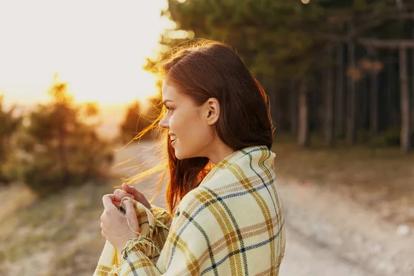 Joyful traveler on a path in the forest with a plaid blanket on her shoulders —  Fotos de Stock