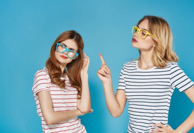 Çizgili tişörtlü iki kız kardeş iletişim duyguları mavi arka planda kavga ediyor