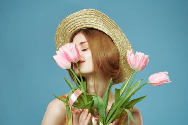 Çiçekli güzel bir kadın. Yüzünün yanındaki şapka. Gülümse.