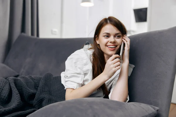 Cheerful woman talking on the phone lying on the couch — Stock Photo, Image