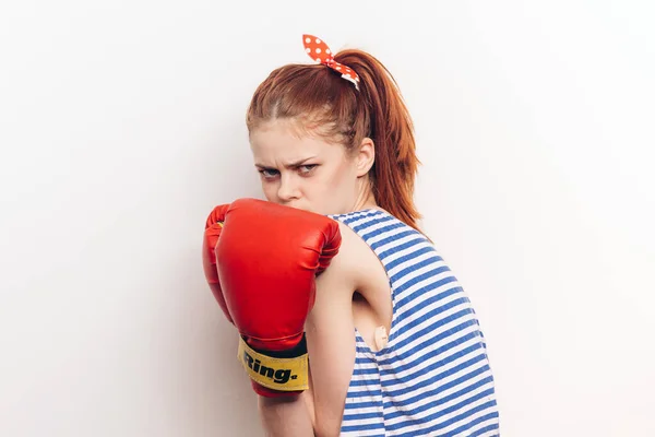 Starke Frau in Boxhandschuhen und gestreiftem T-Shirt auf leichtem Aggressionsmodell — Stockfoto