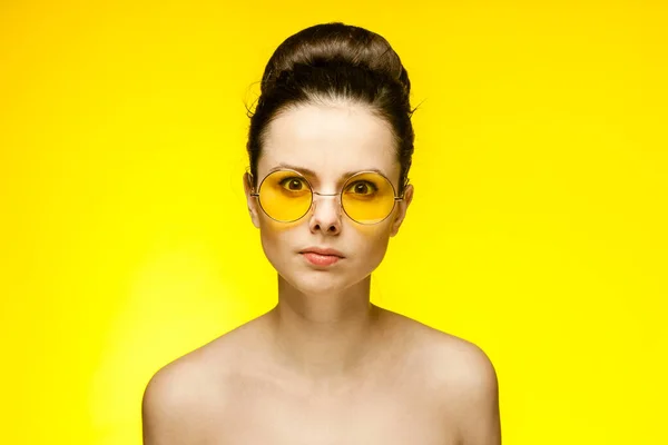 Güzel, çıplak omuzlu, duyguları olan, şık sarı gözlükleri olan bir kadın. — Stok fotoğraf