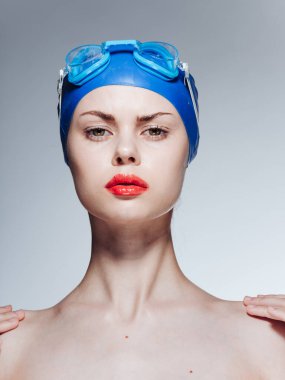 Mavi gözlüklü, yüzme şapkalı, omuzları açık bir kadın.