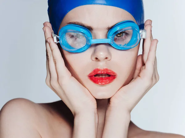戴着蓝色泳帽的漂亮女人用手和眼镜触摸着她的脸 — 图库照片