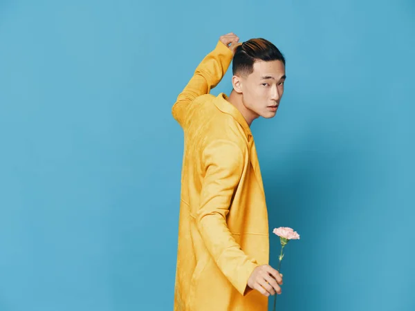 黄色のコートに青い背景で花が舞う男 — ストック写真