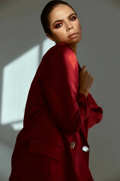 밝은 메이크업 모델을 보고 있는 빨간 자켓을 입은 여자 — 스톡 사진