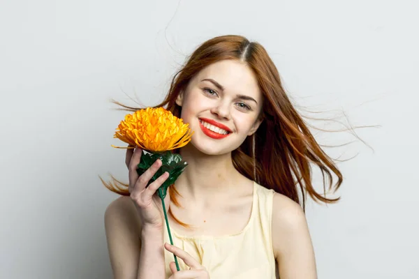 Séduisante femme aux cheveux roux avec fleur jaune près du visage glamour studio — Photo