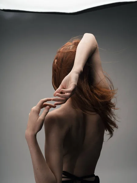 Nude red-haired woman touching herself with hands cropped back view