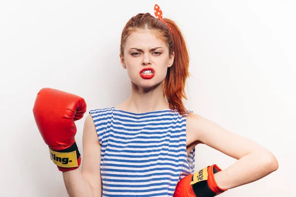 Frau boxt auf hellem Hintergrund rote Handschuhe Sport gestreiftes T-Shirt — Stockfoto