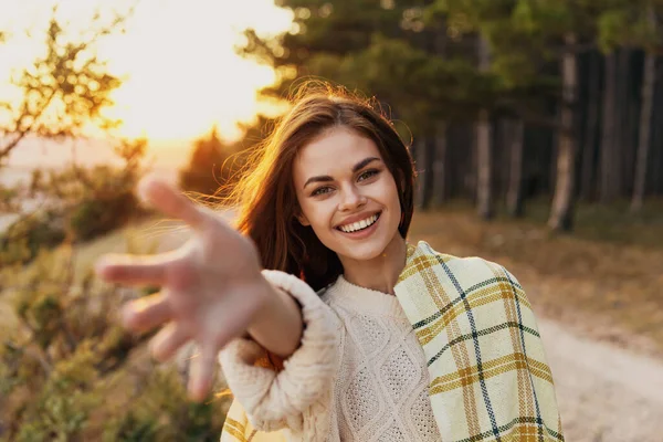 Gelukkig vrouw strekt haar hand naar voren op de natuur in de buurt van groene struiken — Stockfoto