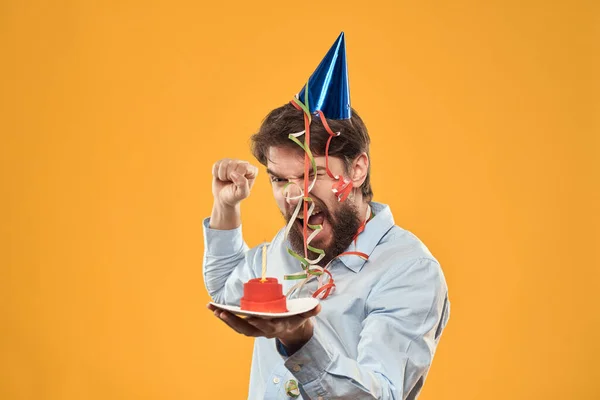 Guy avec un gâteau dans une assiette sur un fond jaune vacances bougie vue recadrée — Photo