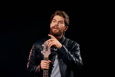 Elinde gitar olan bir adam deri ceketli müzik performansı rock yıldızı modern tarz koyu arkaplan