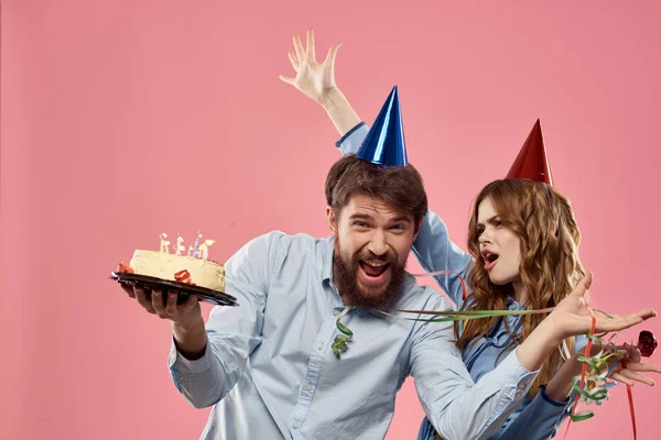 분홍색 배경 회사 생일에 케이크를 갖고 있는 남녀 — 스톡 사진