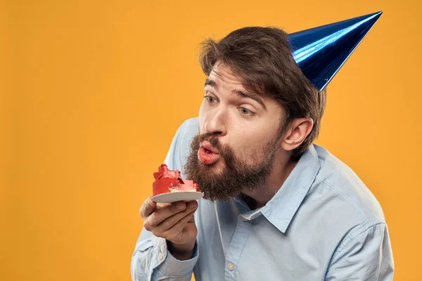 Homme avec gâteau sur fond jaune chapeau de fête anniversaire vue recadrée — Photo