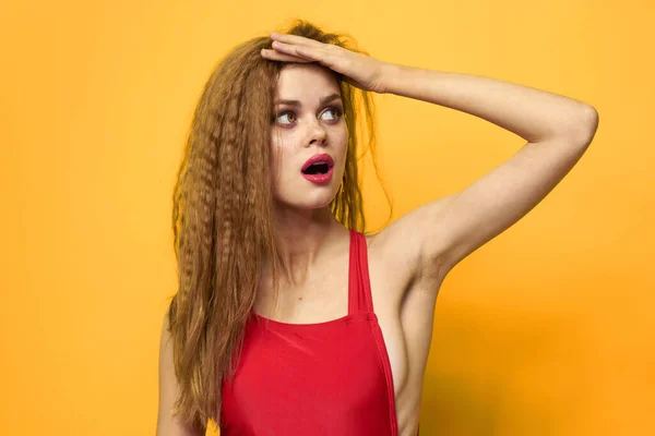 Mujer bonita pelo ondulado tanque rojo top moda estilo de vida cosméticos fondo amarillo — Foto de Stock