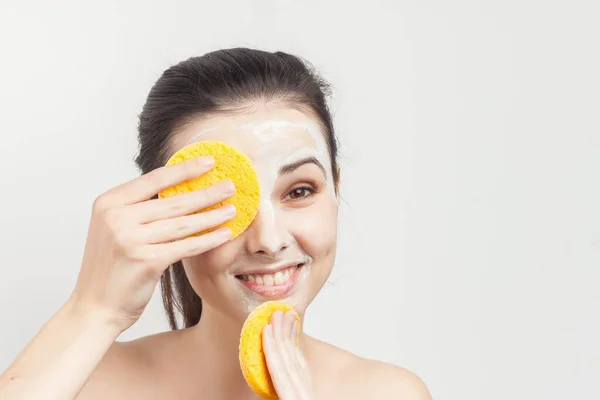 Morena alegre limpa máscara facial com esponjas vista cortada — Fotografia de Stock