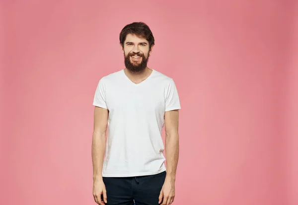 Barbudo cara em uma camiseta e calças em um fundo rosa — Fotografia de Stock