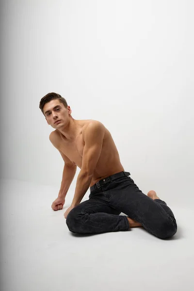 Samec nahoře bez sedí na podlaze černé kalhoty model — Stock fotografie